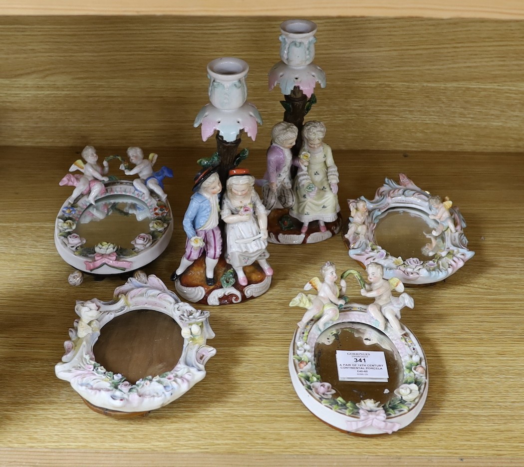 A pair of 19th century continental porcelain figural candlesticks and a group of four similar frames